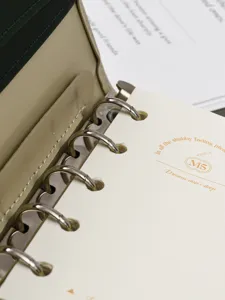 Primo piano dettagliato del mini planner ad anelli con meccanismo in metallo e copertina.