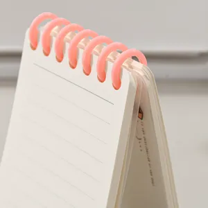 Mini carnet à spirale avec anneaux roses et papier ligné pour la prise de notes portable.