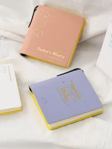 Primer plano detallado de un mini cuaderno bonito con diseño de gato dorado y portabolígrafos.