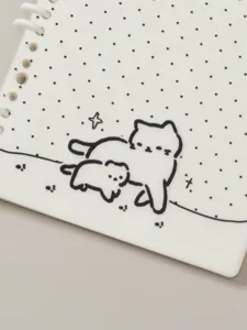 Detailopname van A5 notitieboekpagina's met schattige kattenillustratie en stippenlijnen.