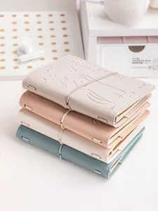 Detailed view of a stack of four colorful faux leather travel journals with embossed cat motifs