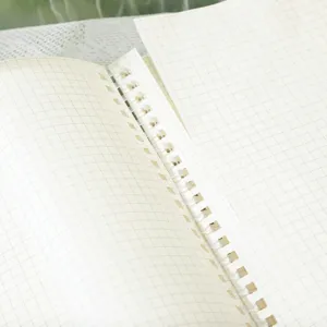 Detailopname van een zacht spiralen notitieboek in B5-formaat met ruitjes en handige scheurrandpagina's.