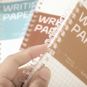 Gedetailleerde close-up van een spiralennotitieboek met ruitjespapier en plastic inbindring.
