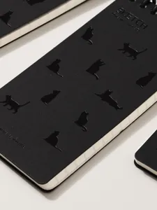 Black spiral notebook featuring embossed cat silhouettes and sleek cover design for daily writing.