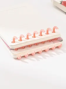Detalle en primer plano del cuaderno A7 con anillas desmontables rosas y páginas rayadas.