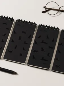 Black pocket notebook detail view featuring cute cat silhouette embossing and coil binding.