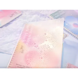 Close-up of pink gradient waterproof cover on soft spiral notebook with water droplets