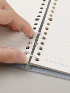 Cuaderno de hojas sueltas detalle con anillas transparentes y páginas rayadas para estudiantes.
