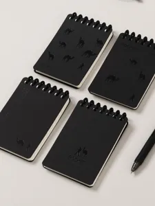Detalle de cuadernos de notas de bolsillo en espiral negros con relieves de camellos.