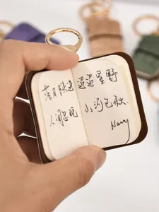 Dettaglio del mini portachiavi taccuino in pelle PU con pagine di poesie scritte a mano.