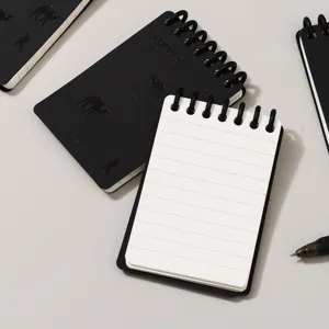 Cuaderno de bolsillo de hojas sueltas A7 con cubierta negra y páginas rayadas, diseño en espiral.