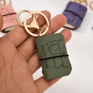 Portachiavi mini in pelle PU a forma di libro con simpatico orsetto e anello metallico.