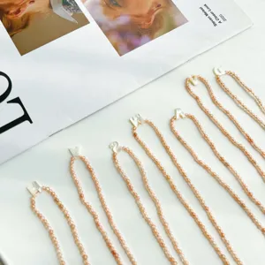 Λεπτομέρεια από ροδακινί κολιέ με χάντρες και λευκά γράμματα από κοχύλι