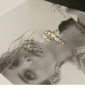 Close-up detail of French style J-shape silver and gold earrings with clear zirconia