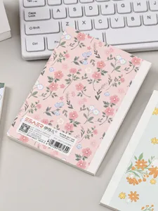 Vista detallada del cuaderno A6 floral rayado, diseño plano sobre un escritorio blanco.