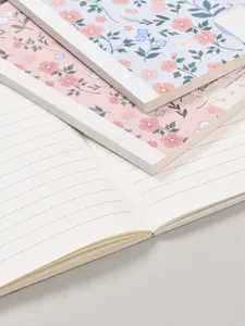 Detalle del cuaderno floral con bonita cubierta de flores rosas y azules y páginas interiores rayadas.