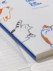 Vue détaillée de la couverture de carnet blanche pailletée avec des motifs de chats.
