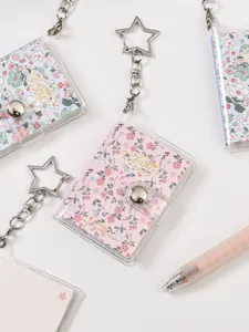 Mini transparent photo album keychain with cute floral cover and metal star clasp detail.
