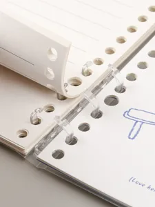 Close-up detail of 6-ring loose leaf notebook with clear rings and lined pages for students.