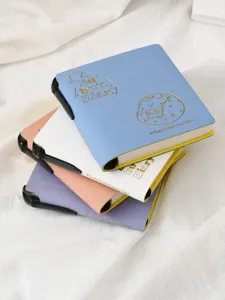 Primer plano detallado de coloridos diarios estudiantiles con portalápices integrado.