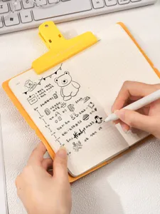 Gros plan d'une main écrivant dans un joli carnet illustré à grille jaune