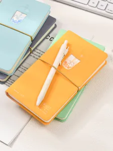 Gros plan d'un carnet orange motif chat thé perlé avec un stylo blanc.