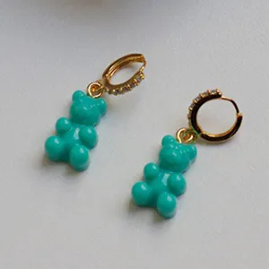 Dettaglio degli orecchini a forma di orsetto gommoso turchese con cerchi d'oro e zirconi.