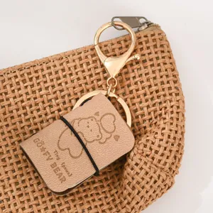 Grazioso portachiavi mini quaderno in pelle PU con accessori dorati per zaino.