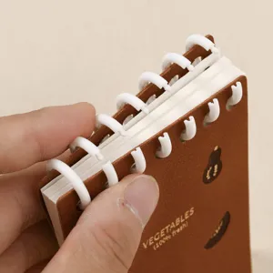 Tascabile taccuino A7 con copertina in pelle marrone e anelli bianchi per appunti quotidiani.