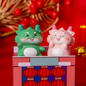 Close-up of cute green and pink resin dragon figurines for festive New Year tabletop decor.