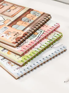 Close-up of stacked A4 spiral sketchbooks with colorful wire binding and illustration covers