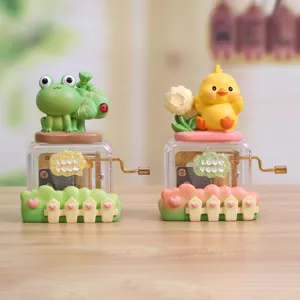 Detailed view of hand-crank music boxes with cute frog and chick figurines