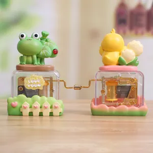 Detail view of connected hand-cranked music boxes featuring cute frog and chick figurines