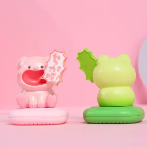 Close-up detail of cute resin pig and frog fragrance box ornaments on pink background