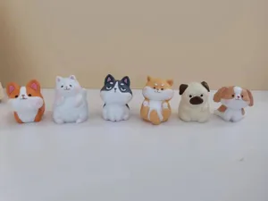 Vue détaillée de six figurines de chiens miniatures en résine alignées sur une surface blanche
