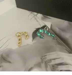 Close-up detail of French style J-shaped earrings featuring white and green zircon stones