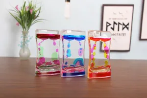 Close-up of three colorful liquid motion bubbler timers on a wooden desk for home decor.