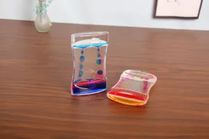 Detailed view of two dual-color liquid motion bubbler timers on a wooden desk surface