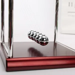Primer plano de bolas metálicas de péndulo de Newton sobre una base roja