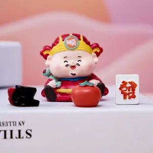 Close-up view of a cute God of Wealth figurine featuring a mini mahjong tile and persimmon