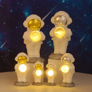 Detail of glowing astronaut ornaments with metallic visors against a starry sky