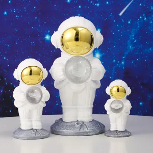 Set of three white astronaut figurines with golden visors and starry glass crystal spheres