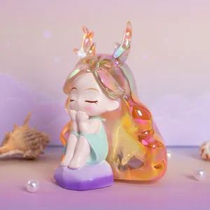 Primo piano di una statuina in resina fata daydream iridescente su sfondo pastello