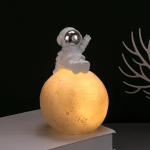 Astronauta creativo seduto su una lampada a luna luminosa per decorazione camera e regalo