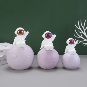 Set di tre statuette creative di astronauti in resina su basi lunari color lavanda.