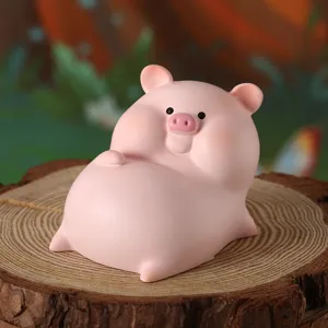 Primo piano di una simpatica statuina di maiale rosa in resina su un ceppo di legno.