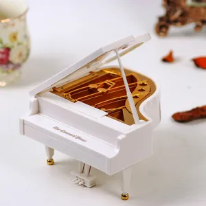 Detailed macro view of an elegant white miniature grand piano music box with golden accents.