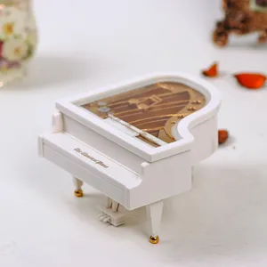 Close-up view of white miniature grand piano music box with visible gold mechanisms