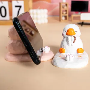 Gros plan de mignons supports de téléphone canard en résine rose et blanc pour bureau