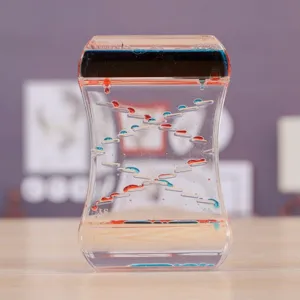 Gros plan d'un jouet sablier liquide bicolore sur bureau